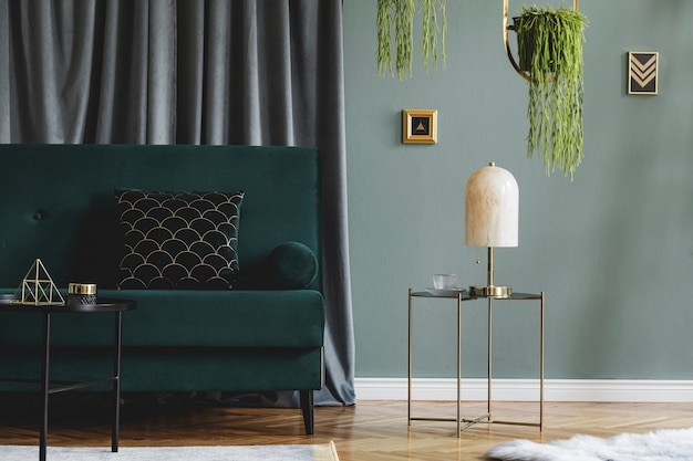 Composition élégante de l'intérieur du salon de l'appartement de luxe avec canapé design, table basse et accessoires. Murs végétalisés et parquet en bois.