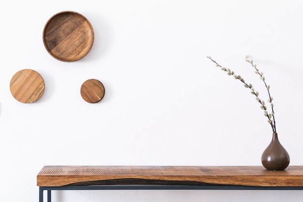 Composition élégante de l'intérieur du salon avec mur blanc, plantes vertes dans des pots blancs conçus par des hipsters sur la console scandinave en bois. Concept minimaliste. Espace de copie. Modèle.