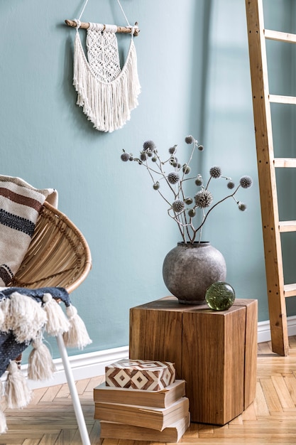 Composition élégante d'un intérieur de salon créatif et confortable avec table basse, fauteuil en rotin, plantes, tapis et accessoires .boho. Murs d'eucalyptus et parquet.