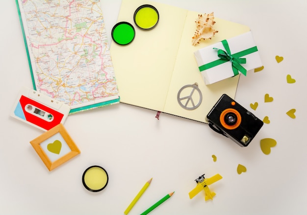 Composition d'éléments de voyage avec appareil photo, jouet d'avion, carte, cahier, symbole de paix et autres éléments