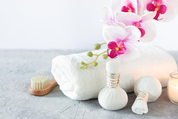 Composition avec équipement de spa pour massage aux herbes et orchidée avec serviette douce sur fond blanc