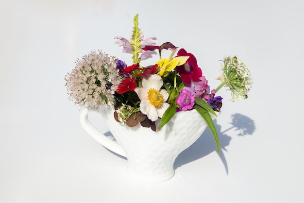 Photo composition estivale de belles fleurs colorées dans un vase sur la table. fond blanc. jeu d'ombre et de lumière. lumière du soleil. décor naturel.