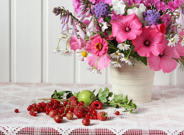 Composition d'été avec des fleurs et des baies sur la table jardin bouquet framboise groseille groseille et pomme verte