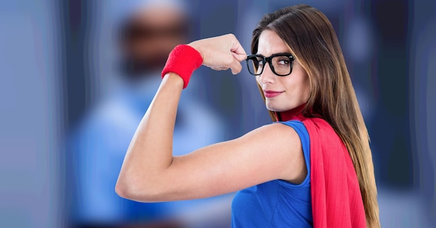 Composition de femme à lunettes habillée en super-héros fléchissant les muscles sur fond médical flou