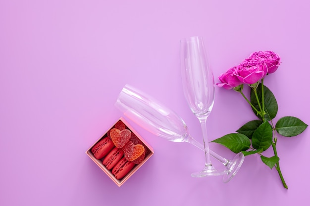 Composition festive pour la Saint-Valentin. Rose rose, boîte avec macarons et verres