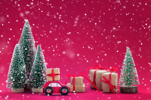 Composition festive Voiture rouge de Noël avec un coffret cadeau dans une pinède où de nombreux cadeaux différents Couleur de l'année 2023