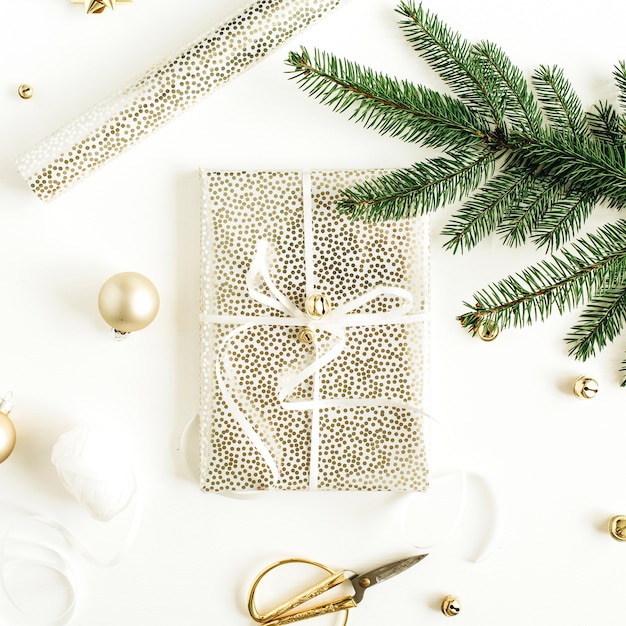 Composition de fête de Noël avec boîte-cadeau décorée, branches de sapin sur une surface blanche. Mise à plat, vue de dessus