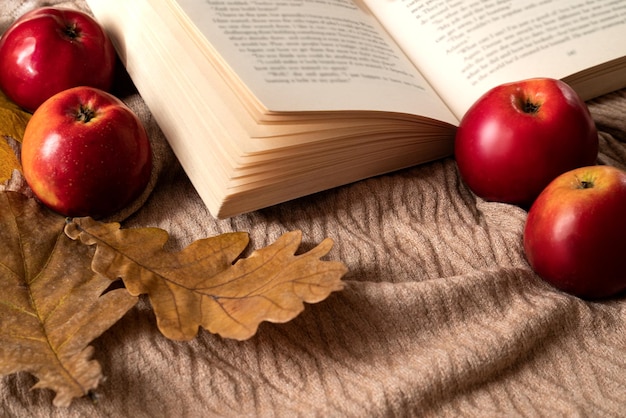 Composition flaylay automnale avec des pommes mûres rouges et des feuilles de chêne sèches éparpillées autour d'un livre ouvert