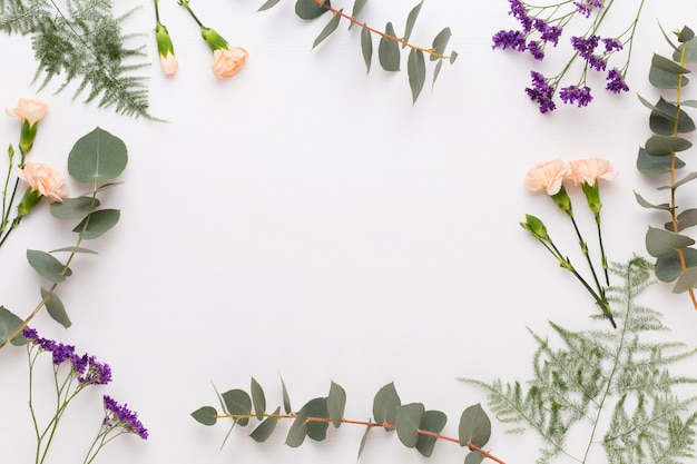 Composition de fleurs. Papier vierge, fleurs d'oeillet, branches d'eucalyptus. Mise à plat, vue de dessus.