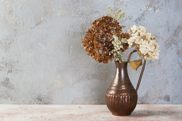 Composition de fleurs séchées dans une cruche en cuivre vintage