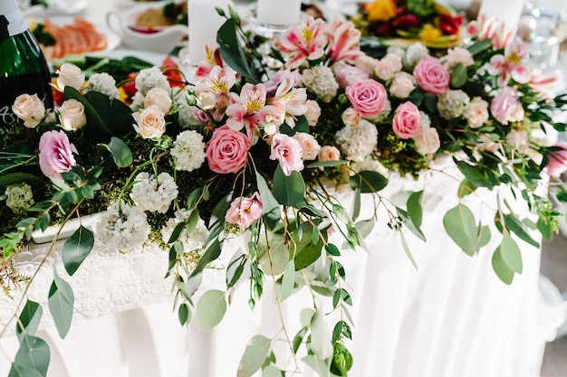 Une composition de fleurs et de vert est sur une table de fête à la salle de banquet de mariage Gros plan