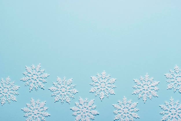 Composition de flocon de neige à paillettes blanches sur fond bleu pastel