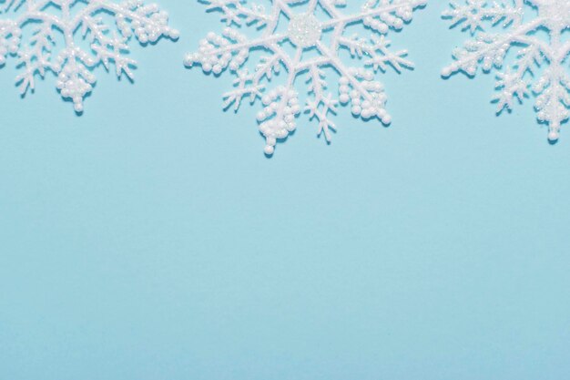 Composition de flocon de neige à paillettes blanches sur fond bleu pastel