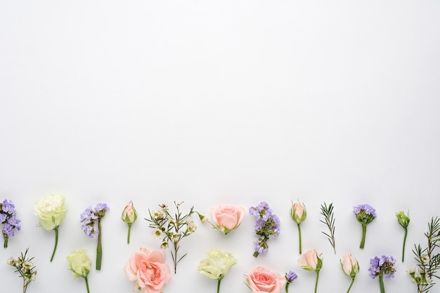 Composition florale de boutons de rose, eustoma, inflorescences de limonium sur blanc