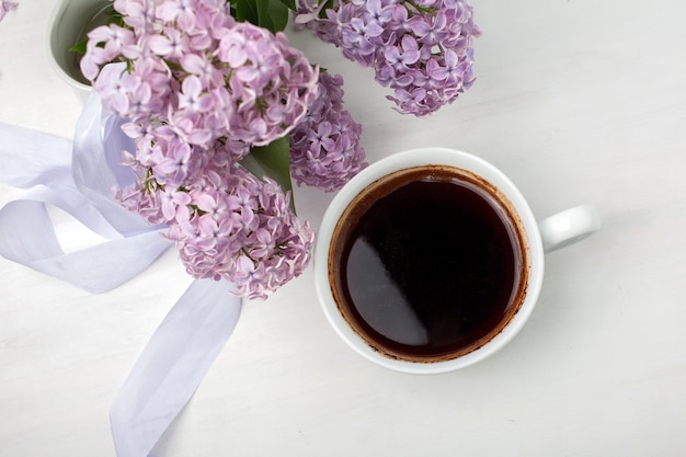 Composition florale faite de beau lilas violet sur fond en bois blanc avec une tasse de café, style stock image, plat, vue de dessus