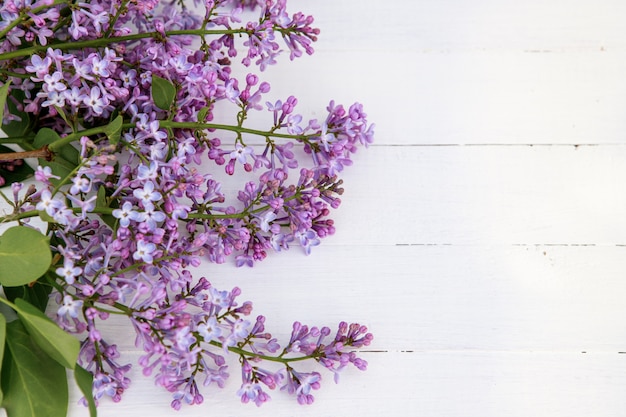 Composition florale de fleurs lilas sur un fond en bois blanc.