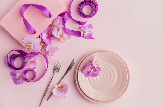 Composition de frais généraux de paramètres de fleurs et de table sur une surface rose clair