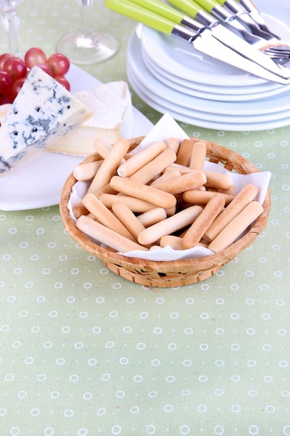 Composition avec fromage raisin et bâtonnets de pain sur plaque sur table sur fond d'un sac