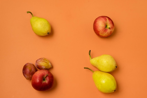 Composition de Fruits sur Fond Orange Pommes Poires Plims Fond Orange