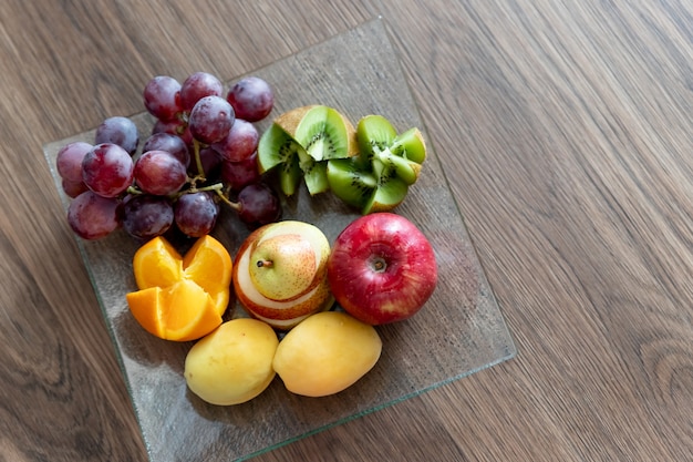 Composition avec des fruits frais mélangés sur une assietteassortiment de fruits juteux sur une assiette de fruits de table en bois ...