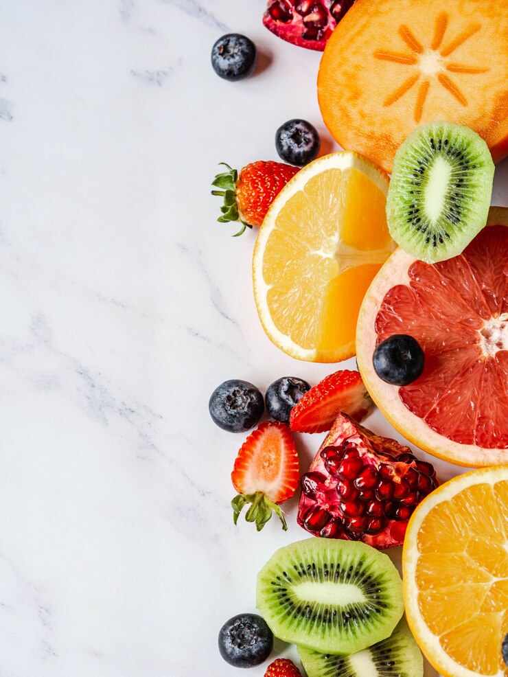 Photo composition de fruits naturels sains multicolores de saison avec kaki, bleuets, orange, kiwi, fraises, pamplemousse, grenade, tranches d'orange.