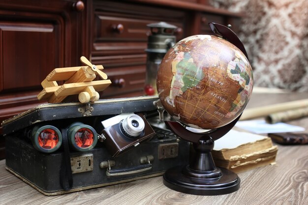 Composition sur un globe vintage en bois avec une vieille valise en cuir avec des objets de voyage