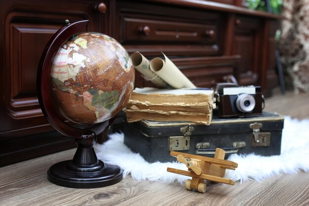 Composition sur un globe vintage en bois avec une vieille valise en cuir avec des objets de voyage
