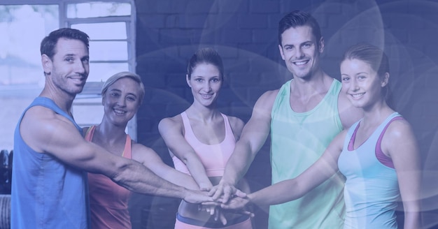 Photo composition d'hommes et de femmes souriants empilant les mains dans un cours de fitness avec des projecteurs