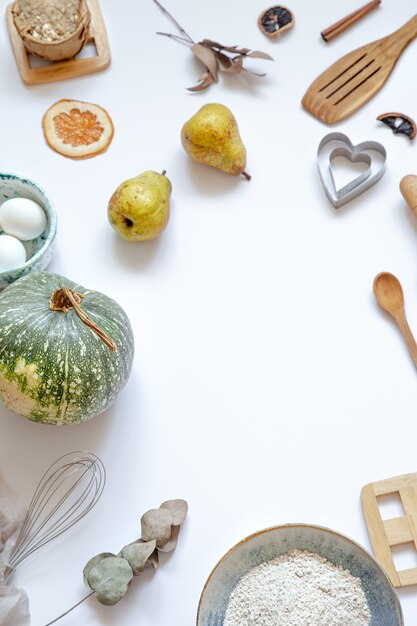 Composition avec des ingrédients de cuisson et des accessoires de cuisine sur une vue de dessus de table blanche.