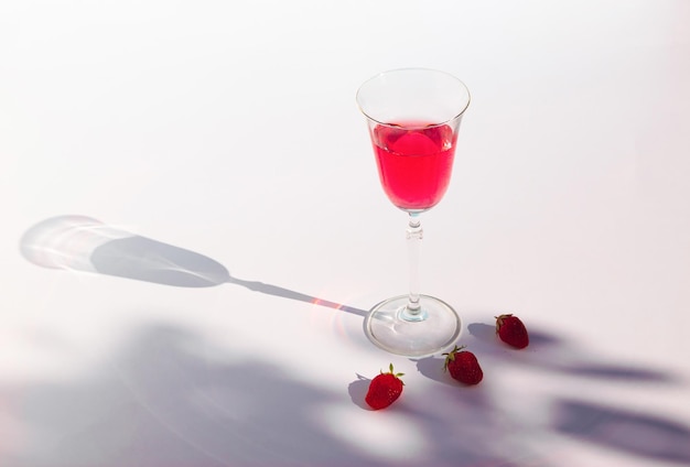 Composition avec jus rouge frais de fraises et ombre de branche Concept de boisson estivale minimale