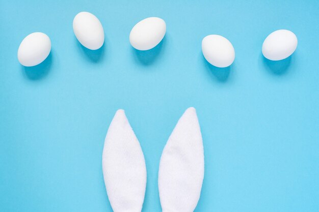 Photo composition laïque à plat des oreilles créatives de lapin de pâques sur fond bleu, espace pour le texte