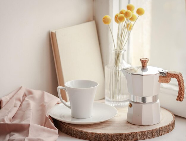 composition légère et aérée de style blanc sur le rebord de la fenêtre d'une cafetière et d'une tasse à café