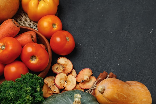 Composition de légumes avec des citrouilles, des tomates et des pommes sèches sur fond noir vue de dessus