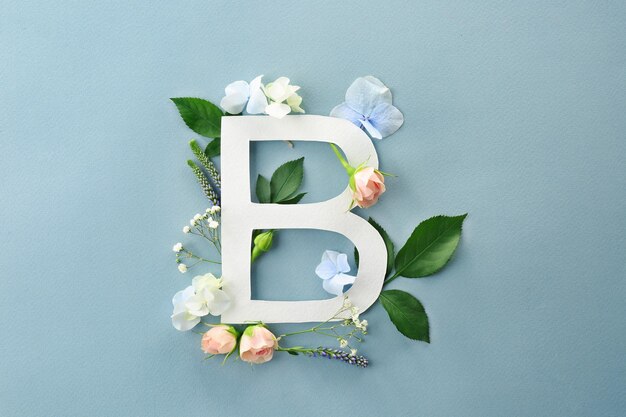 Composition avec lettre B et belles fleurs sur fond de couleur