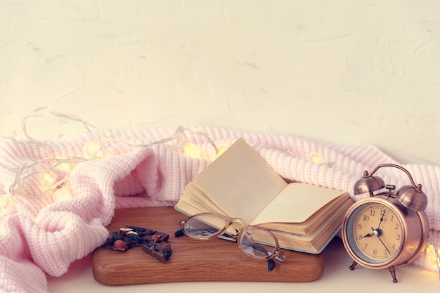 Composition avec livre blanc ouvert, lunettes et réveil rétro