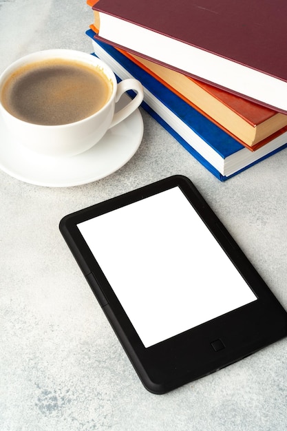 Composition avec livre relié de lecteur de livre électronique moderne et tasse de café sur la table