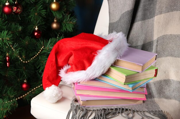 Composition avec livres et plaid, chapeau rouge, sur chaise sur fond d'arbre de Noël