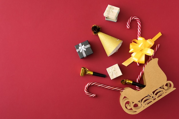 Composition de magasinage avec des cadeaux de Noël, ruban, bonbons en traîneau de Noël sur bannière rouge