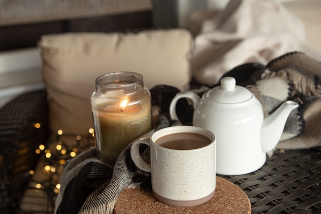 Composition de maison confortable avec une tasse de café, une bouilloire et une bougie allumée. Concept de confort à la maison.