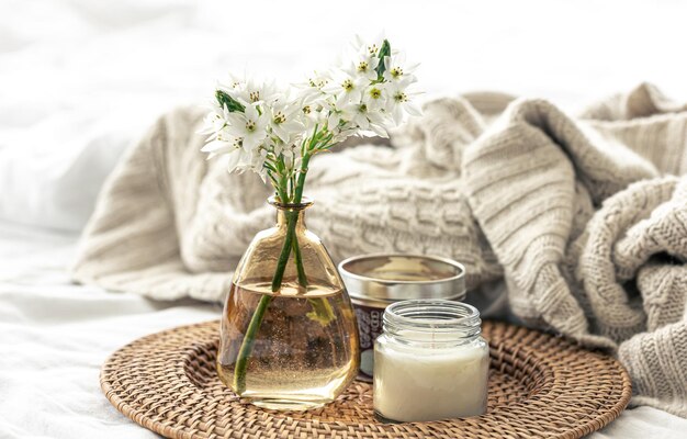 Composition maison avec des fleurs dans des vases et un élément tricoté