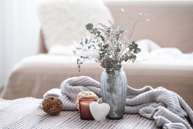 Composition maison avec un vase en verre avec des fleurs séchées et un coeur décoratif