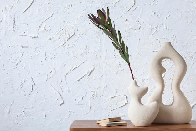Composition minimaliste créative de l'intérieur de la maison avec des vases en argile faits à la main, une table d'appoint et des accessoires personnels élégants. Espace de copie. Fond d'écran. Modèle.