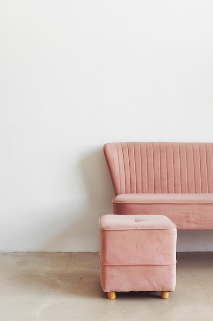 Composition minimaliste de l'intérieur de la pièce avec pouf et canapé roses contre l'espace de copie du mur blanc