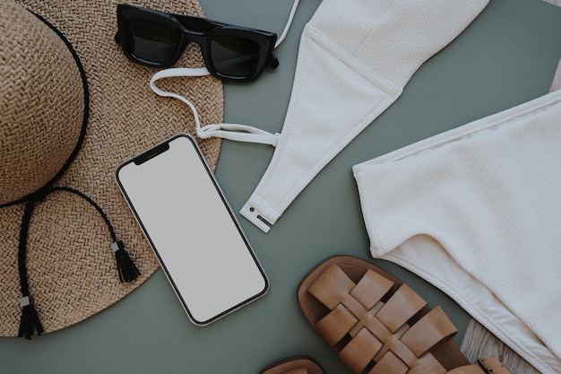 Composition de mode d'été féminine avec chapeau de paille, lunettes de soleil, sandales sur fond pastel Smartphone avec écran d'espace de copie