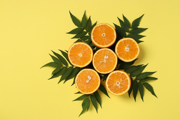 Composition de moitiés d'oranges avec des feuilles vertes sur fond jaune vif Mise à plat Copier l'espace