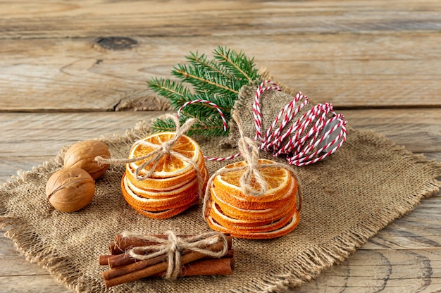 Composition de Noël. Arrangement d'oranges sèches, de bâtons de cannelle, de branches d'arbres à fourrure et de noix sur fond de bois. Ingrédients rustiques, épices de vacances.