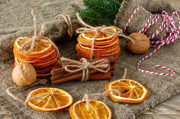 Composition de Noël. Arrangement d'oranges sèches, de bâtons de cannelle, de branches d'arbres à fourrure et de noix sur fond de bois. Ingrédients rustiques, épices de vacances.