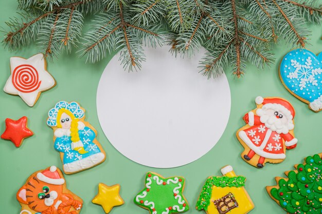 Composition de Noël avec des biscuits colorés de pain d'épice sur le fond vert plat lay copyspace