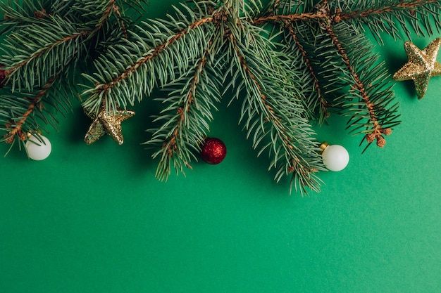 Composition de Noël. Bordure faite d'arbres, décorations rouges et dorées sur vert.