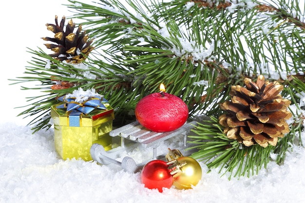 Composition de Noël avec bougie allumée et décorations sur neige